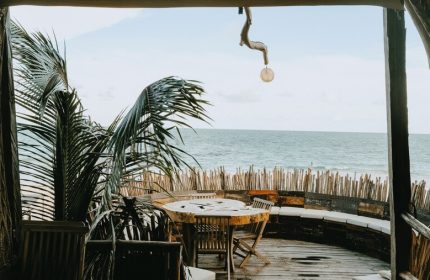 Orchid Beach House Adults Only, gay-friendly hotel. Ocean view from a wooden deck with table, chairs, and palm tree. Relaxing tropical vibe.