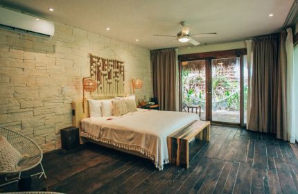 Orchid Beach House Adults Only gay-friendly hotel room. King bed, stone wall, dark wood floor, and patio with hammock. Gay travel.