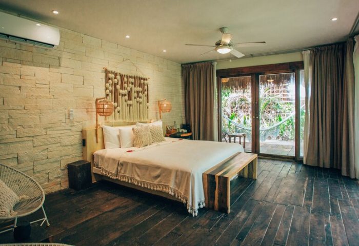 Orchid Beach House Adults Only gay-friendly hotel room. King bed, stone wall, dark wood floor, and patio with hammock. Gay travel.