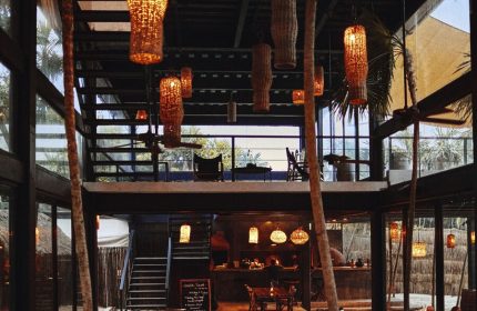 Our Habitas Tulum gay-friendly hotel interior. Rustic design with hanging lamps, tables, and a mezzanine. A stylish, welcoming space.