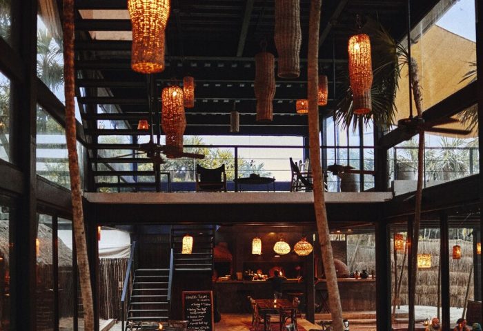 Our Habitas Tulum gay-friendly hotel interior. Rustic design with hanging lamps, tables, and a mezzanine. A stylish, welcoming space.
