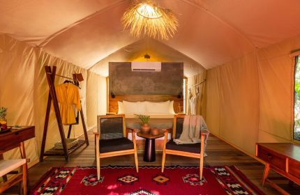 Our Habitas Tulum gay-friendly hotel room. A tented suite with a king bed, chairs, and a red rug. Perfect for gay men's travel in Tulum.