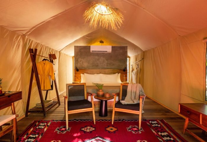 Our Habitas Tulum gay-friendly hotel room. A tented suite with a king bed, chairs, and a red rug. Perfect for gay men's travel in Tulum.