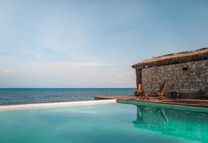 Our Habitas Tulum gay-friendly hotel: Poolside view with ocean backdrop. Relaxing vacation spot for gay men in Tulum, Mexico.