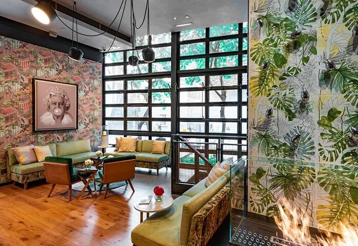 Ovolo Central gay-friendly hotel lounge area. Stylish seating, unique wallpaper, and a portrait of the Queen blowing a bubble. Modern design.