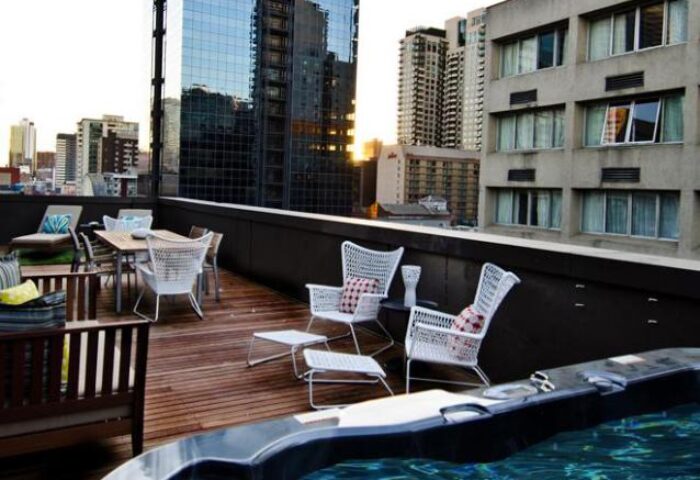 Rooftop terrace at Ovolo Laneways, a gay-friendly and pet-friendly hotel. Features a hot tub, dining area, and city views. Perfect for gay travel.
