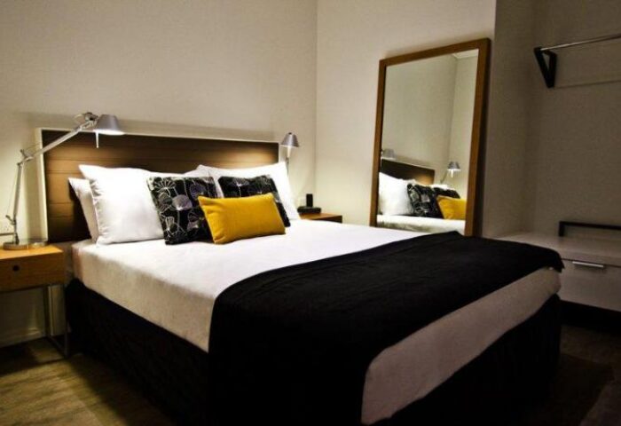 Ovolo Laneways pet-friendly hotel room. Gay-friendly hotel with a bed, pillows, and a mirror. Ideal accommodation for gay travelers and their pets.