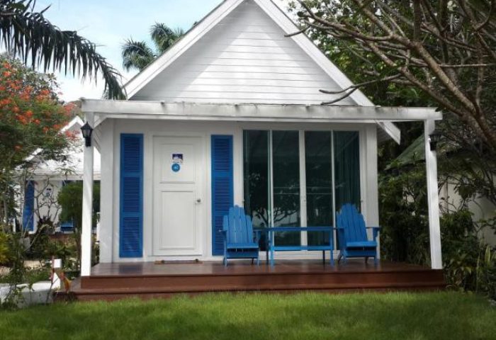 P.P. Blue Sky Resort, a gay-friendly hotel. White bungalow with blue accents, chairs on the porch. Ideal for gay men's travel.