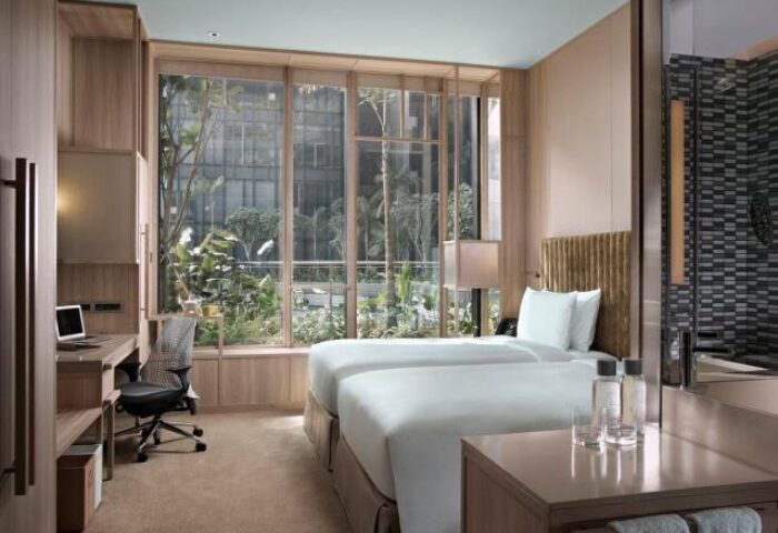 PARKROYAL COLLECTION Pickering Singapore gay-friendly hotel room. Twin beds, desk, and views of lush greenery. Modern design for gay travelers.