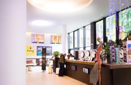 PLUS Berlin Hotel & Hostel lobby. Guests check in at the front desk. Gay-friendly hotel with modern design and travel information.