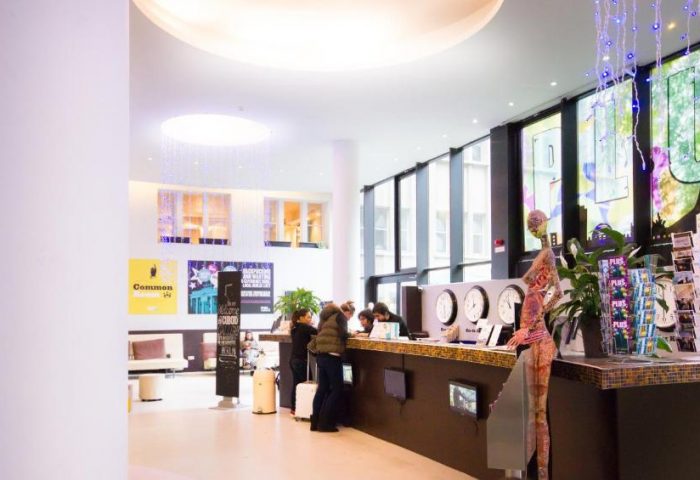 PLUS Berlin Hotel & Hostel lobby. Guests check in at the front desk. Gay-friendly hotel with modern design and travel information.