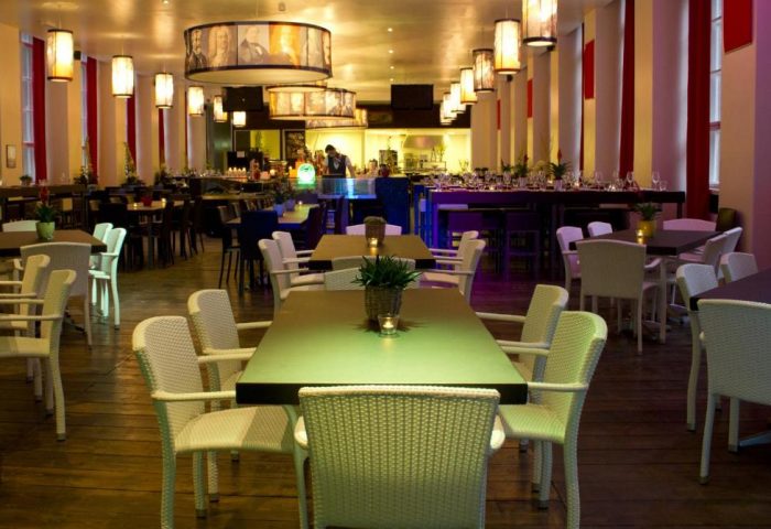 PLUS Berlin Hotel & Hostel's stylish restaurant. Tables and chairs fill the large room with unique lighting. Gay-friendly hotel in Berlin.