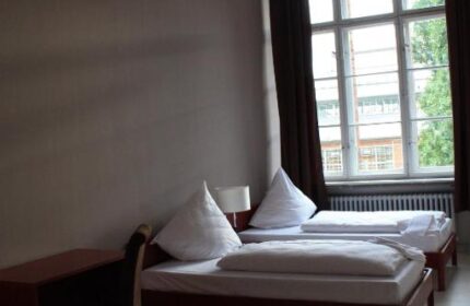 PLUS Berlin Hotel & Hostel room. Twin beds, desk, and large window. Gay-friendly hotel for gay men traveling in Berlin.