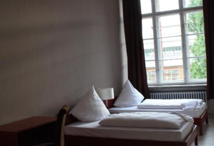 PLUS Berlin Hotel & Hostel room. Twin beds, desk, and large window. Gay-friendly hotel for gay men traveling in Berlin.