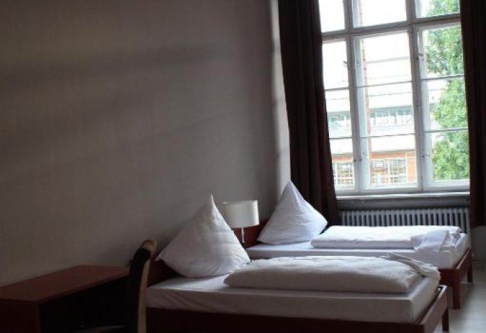 PLUS Berlin Hotel & Hostel room. Twin beds, desk, and large window. Gay-friendly hotel for gay men traveling in Berlin.