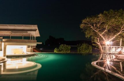 Night view of the pool at PP Charlie Beach Resort, a gay-friendly hotel. Features a bar, trees, and lounge chairs. Perfect for gay travel.