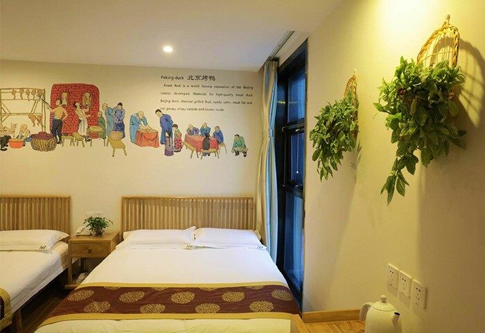 PUREMIND Hutong Courtyard Hotel room. Gay-friendly hotel with twin beds, Peking duck mural, birdcage planters. Beijing travel for gay men.