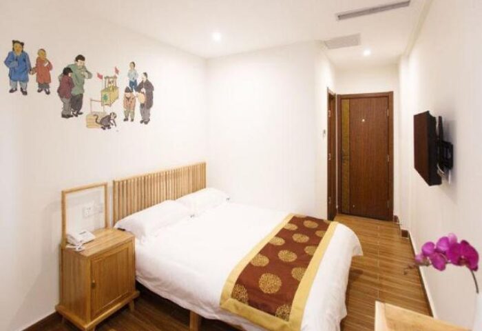 PUREMIND Hutong Courtyard Hotel room. Gay-friendly hotel bedroom with a double bed, TV, and traditional Chinese wall art.