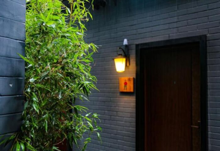 PUREMIND Hutong Courtyard Hotel: Exterior detail of this gay-friendly hotel. A door with a lantern and a stylized man icon. Bamboo plant nearby.