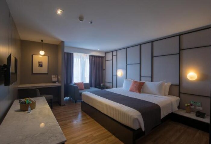 Page 10 Hotel's gay-friendly room: King bed with stylish headboard, desk, and seating area. Perfect for gay men travelers seeking comfort.