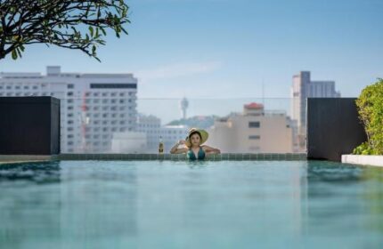 Page 10 Hotel's rooftop pool view. Woman in hat enjoys the infinity pool overlooking the cityscape. Gay-friendly hotel travel.