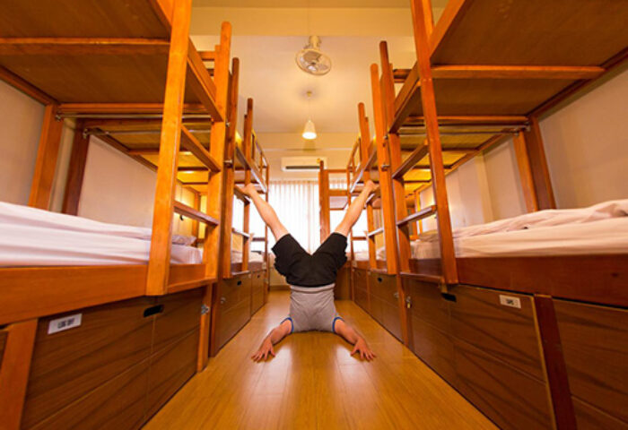 Pak Up Hostel: Man does a headstand in a dorm room with bunk beds. Gay-friendly hotel for gay men travelers.