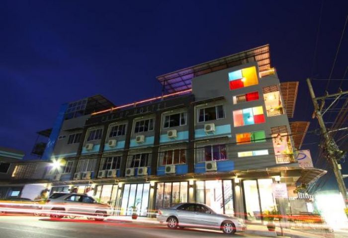 Exterior nighttime view of Pak Up Hostel, a gay-friendly hotel. Building features colorful windows and modern design. Travel advice for gay men.