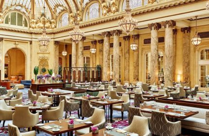 Elegant dining room at the gay-friendly Palace Hotel, a Luxury Collection Hotel, San Francisco. Chandeliers, columns, and tables.