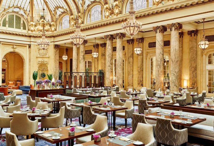 Elegant dining room at the gay-friendly Palace Hotel, a Luxury Collection Hotel, San Francisco. Chandeliers, columns, and tables.