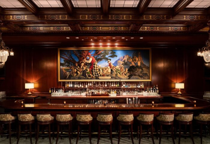 Bar at the gay-friendly Palace Hotel, a Luxury Collection Hotel, San Francisco. Elegant wood paneling, painting, and bar stools. Upscale ambiance.