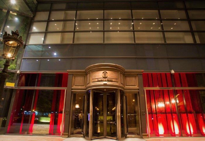 Palais de Chine Hotel entrance. Revolving door, red curtains, and a modern glass facade. Gay-friendly hotel for gay men travel advice.