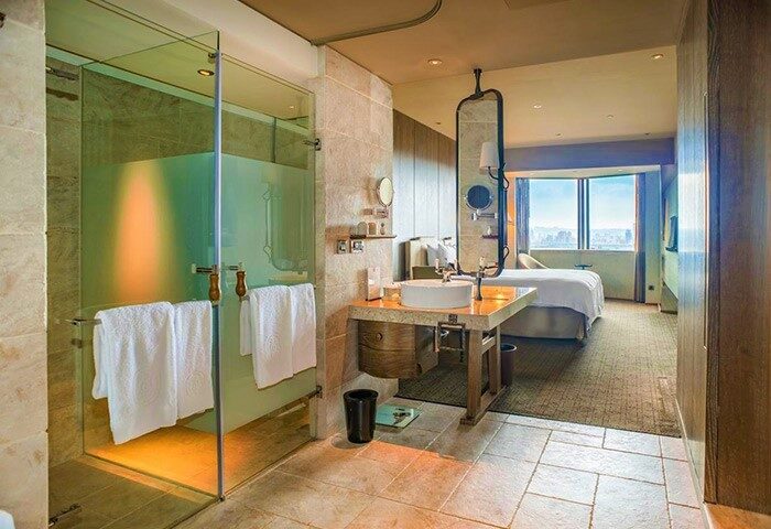 Palais de Chine Hotel gay-friendly room. Modern bathroom with shower, sink, and view of the bedroom. Luxury gay travel in Taiwan.