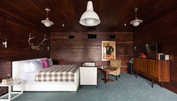 Palihotel Melrose room. Gay-friendly hotel with dark wood paneling, plaid bedspread, vintage furniture, & stag antlers. Stylish, unique design.