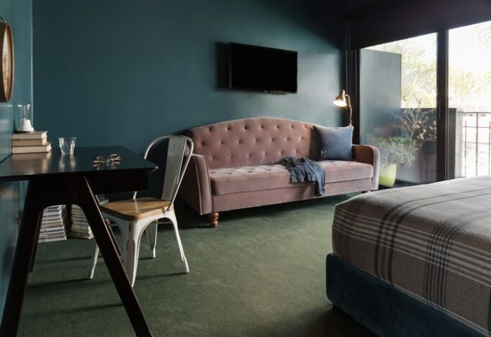 Palihotel Melrose room. Desk, pink sofa, TV, and balcony in a stylish hotel room. Gay-friendly hotel for gay men travel in Los Angeles.