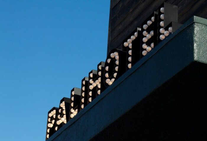 Palihotel Melrose sign. Gay-friendly hotel in Melrose, Los Angeles. The hotel's name is spelled out with illuminated bulbs against a bright blue sky.