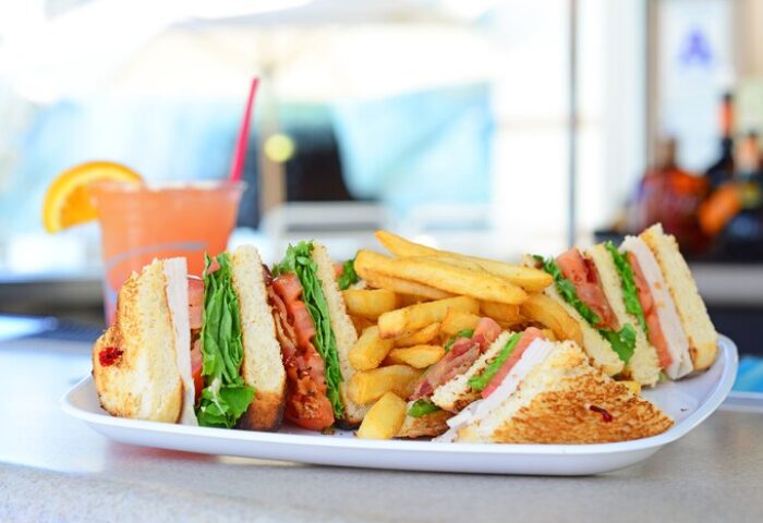 Club sandwich and fries with a drink at Palm Canyon Resort, a gay-friendly hotel in Palm Springs. Hilton Vacation Club dining.