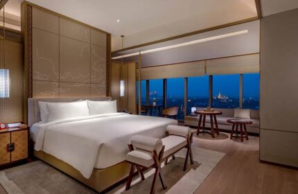 Pan Pacific Yangon hotel room at night. Gay-friendly hotel with a view of the city skyline. Luxury hotel room with a king-size bed and seating area.