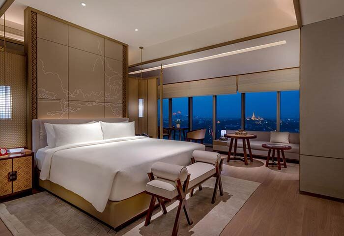 Pan Pacific Yangon hotel room at night. Gay-friendly hotel with a view of the city skyline. Luxury hotel room with a king-size bed and seating area.