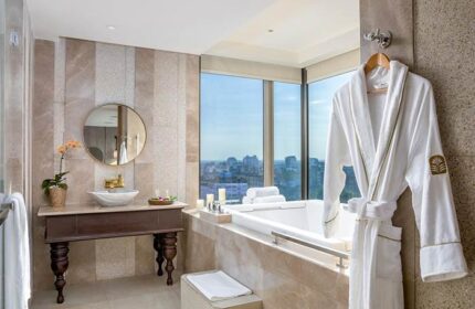 Bathroom in Pan Pacific Yangon, a gay-friendly hotel. Bathtub, sink, robe, and city view. Luxury travel for gay men in Yangon, Myanmar.