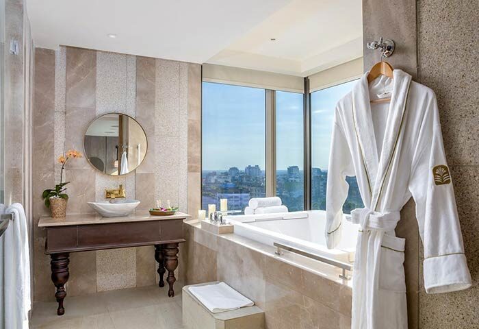 Bathroom in Pan Pacific Yangon, a gay-friendly hotel. Bathtub, sink, robe, and city view. Luxury travel for gay men in Yangon, Myanmar.