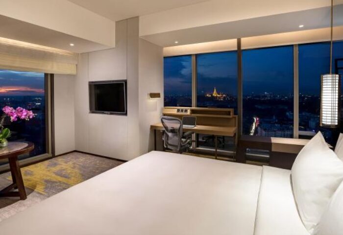 Pan Pacific Yangon gay-friendly hotel room at night. City view, desk, and bed create a luxurious experience for gay travelers.