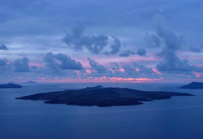 Sunset view from Panorama Boutique Hotel, a gay-friendly hotel. Islands visible in the distance under a cloudy sky. Ideal gay travel destination.