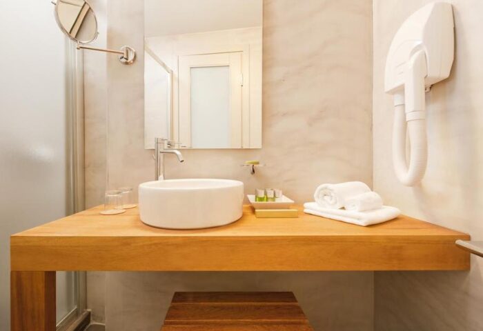 Bathroom at Panorama Boutique Hotel, a gay-friendly hotel. Features a modern sink, mirror, towels, and hairdryer for a comfortable stay.