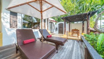 Paradee Resort gay-friendly hotel. Deck with lounge chairs, umbrella, and outdoor seating area. Tropical getaway for gay men travelers.