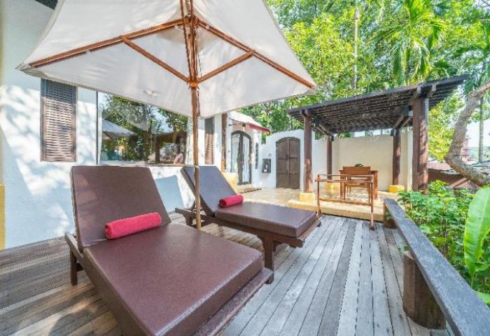 Paradee Resort gay-friendly hotel. Deck with lounge chairs, umbrella, and outdoor seating area. Tropical getaway for gay men travelers.