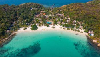 Aerial view of Paradee Resort, a gay-friendly hotel. Tropical beach, turquoise water, and lush greenery offer a serene getaway.