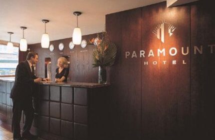 Paramount Hotel reception area. Guest checks in at the front desk. Gay-friendly hotel with modern design, wood paneling, and elegant lighting.
