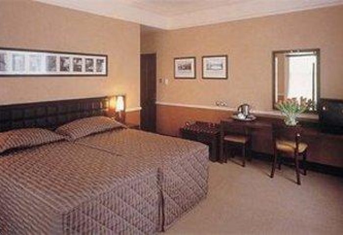 Paramount Hotel room interior. Gay-friendly hotel with double bed, desk, chair, and warm lighting. Comfortable stay for gay men travelers.