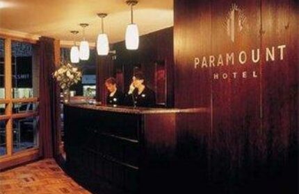 Paramount Hotel reception area. Gay-friendly hotel with staff at the front desk. Warm lighting and wood paneling create an inviting atmosphere.