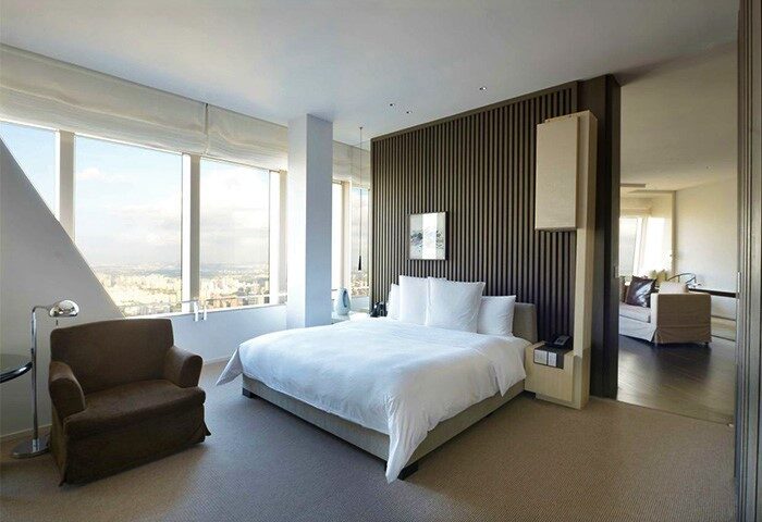 Park Hyatt Shanghai gay-friendly hotel room. Modern design, city view. Luxurious bedroom with king bed, armchair, and view in Shanghai.